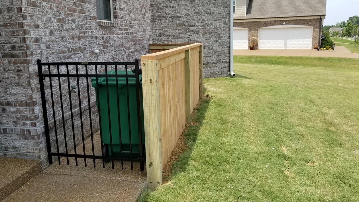 Custom wood and metal trash can enclosure beside brick house