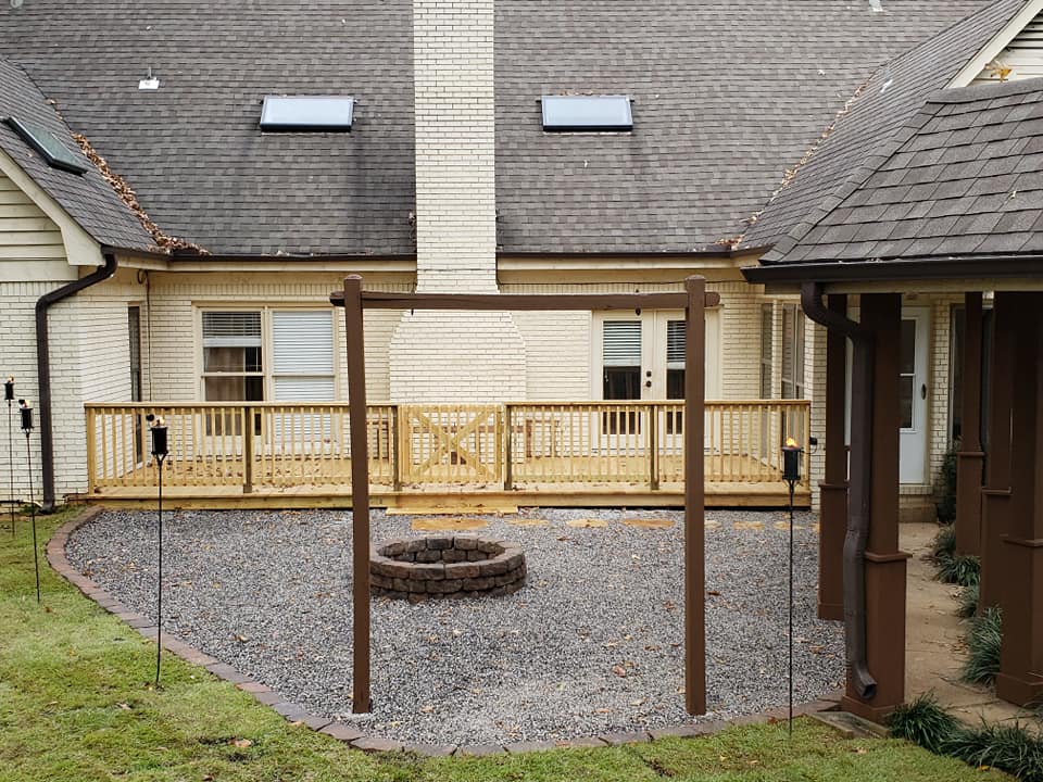 Custom wood deck railing with X-pattern gate and fire pit patio area