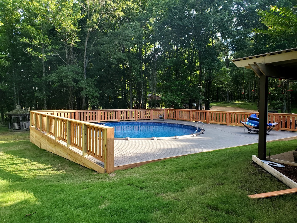 Custom pool deck with wood railing surrounded by trees
