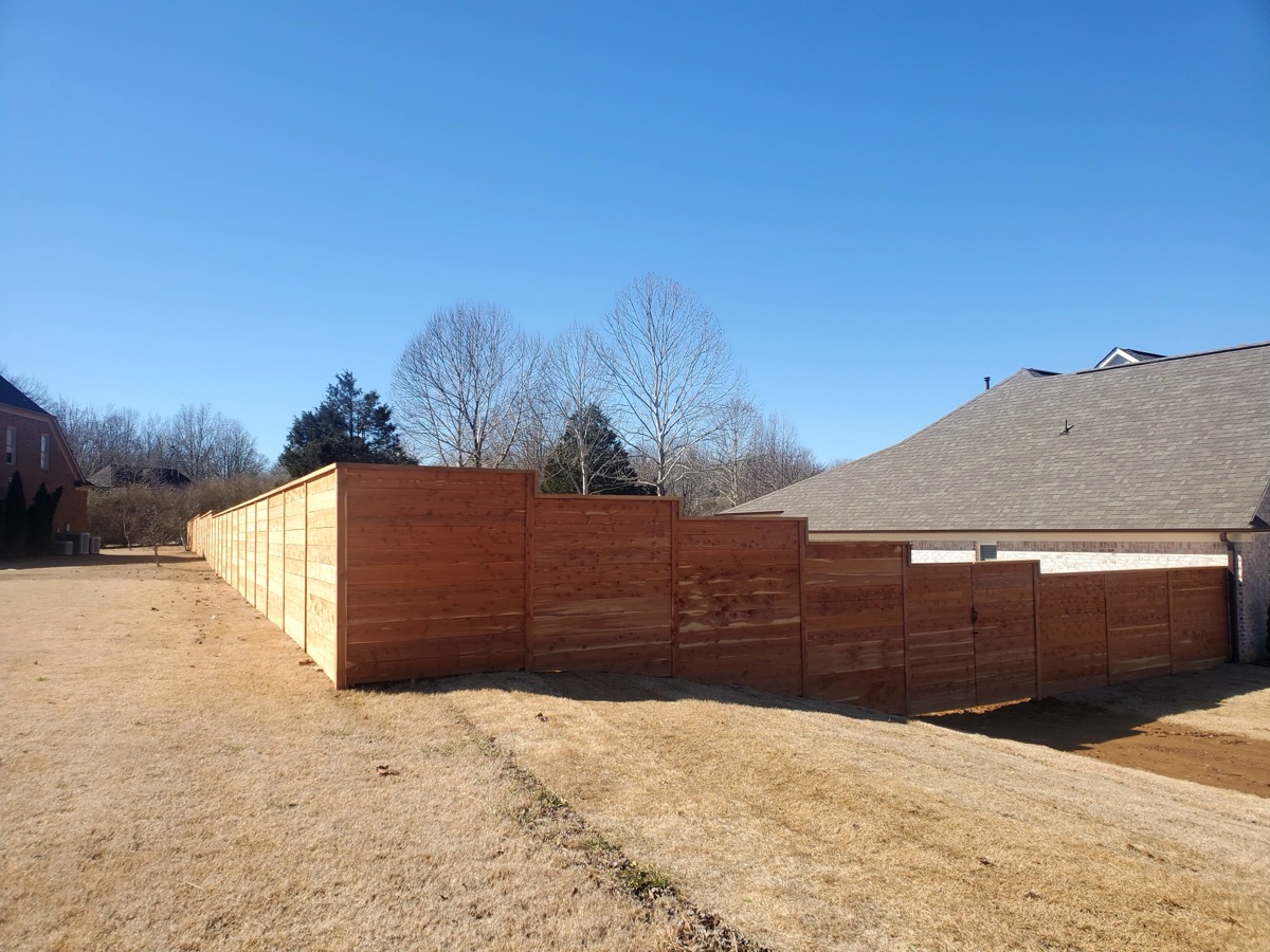 Modern horizontal slat cedar fence along residential property