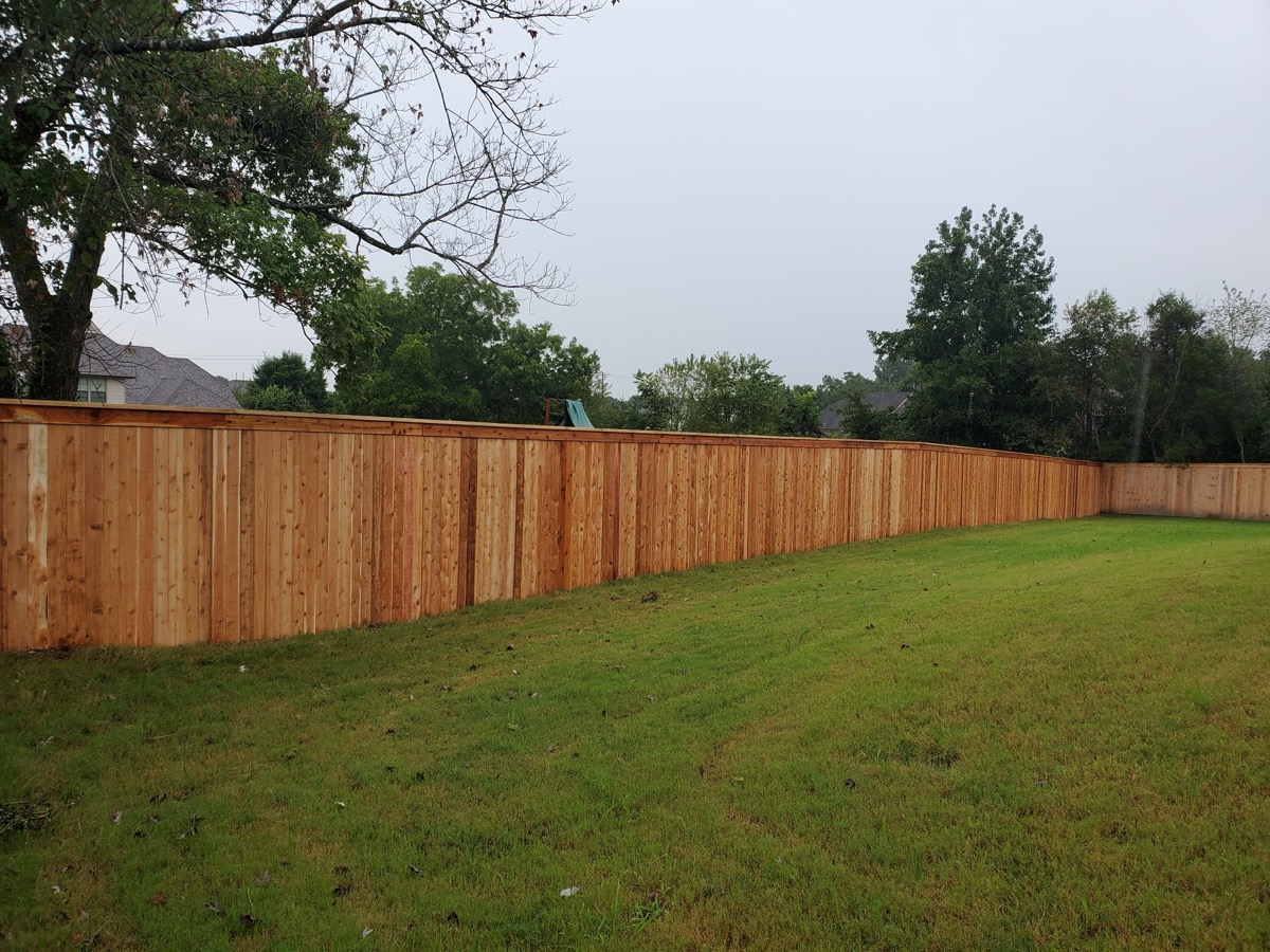 Long run of cedar privacy fence on green lawn