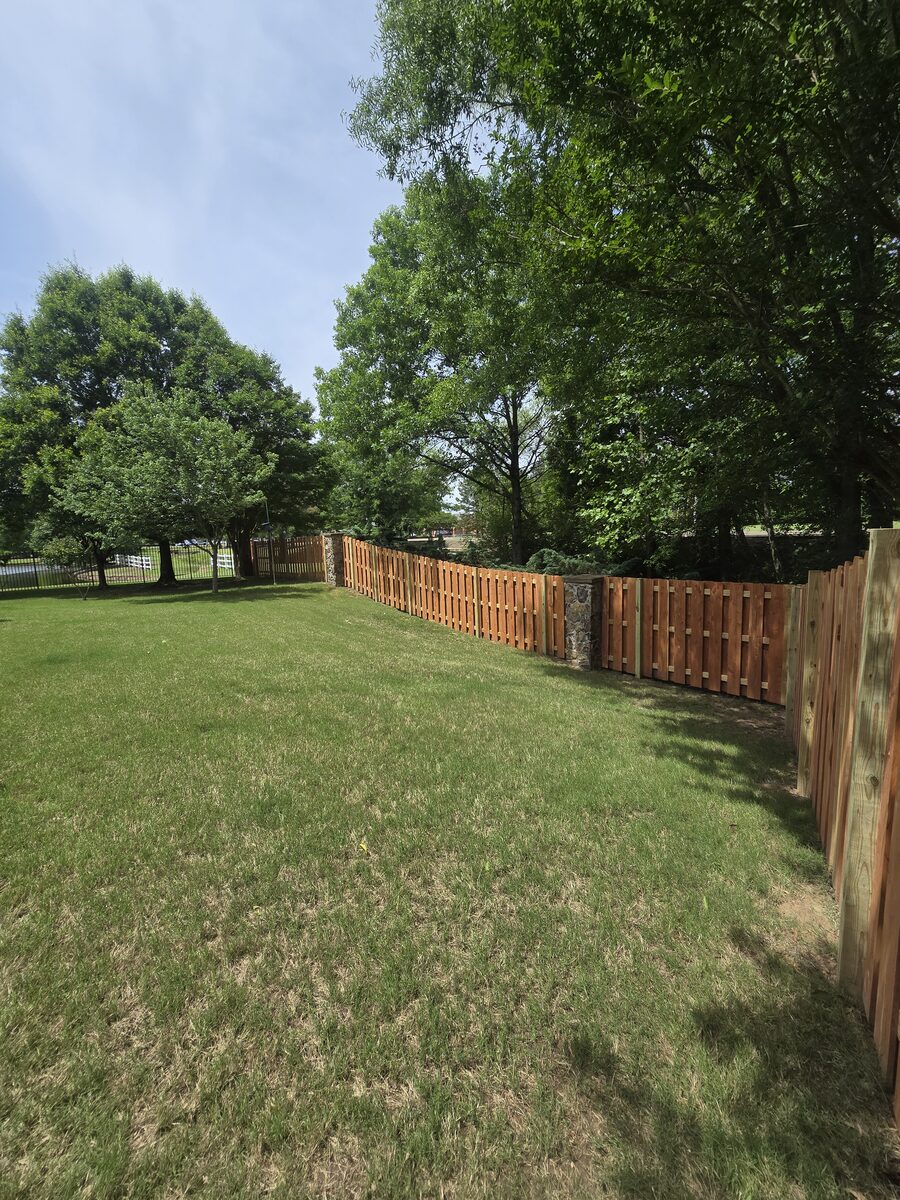 Shadowbox fence corner with stone column in open backyard