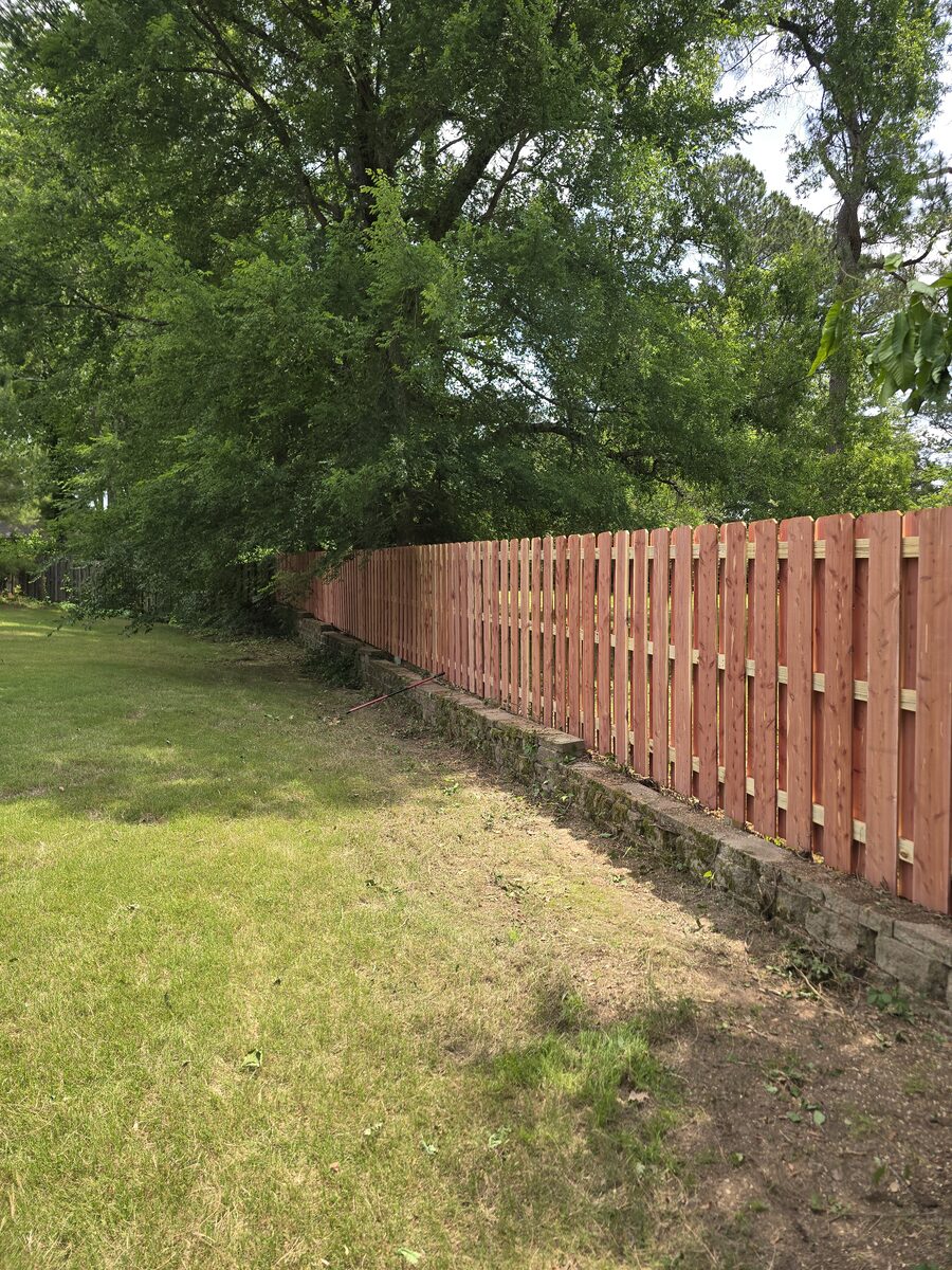 Shadowbox fence built above stone retaining wall on sloped yard