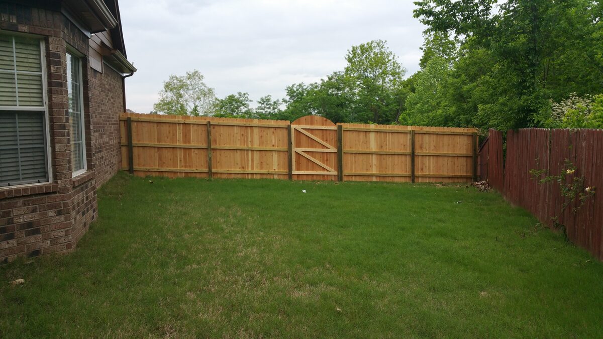 Western cedar fence with arched gate enclosing backyard
