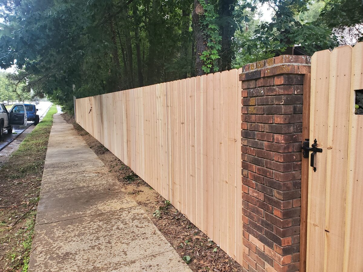 Western cedar fence with brick column and gate along sidewalk