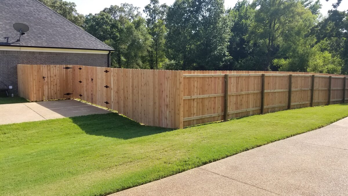 Western cedar fence corner with double gates and manicured lawn