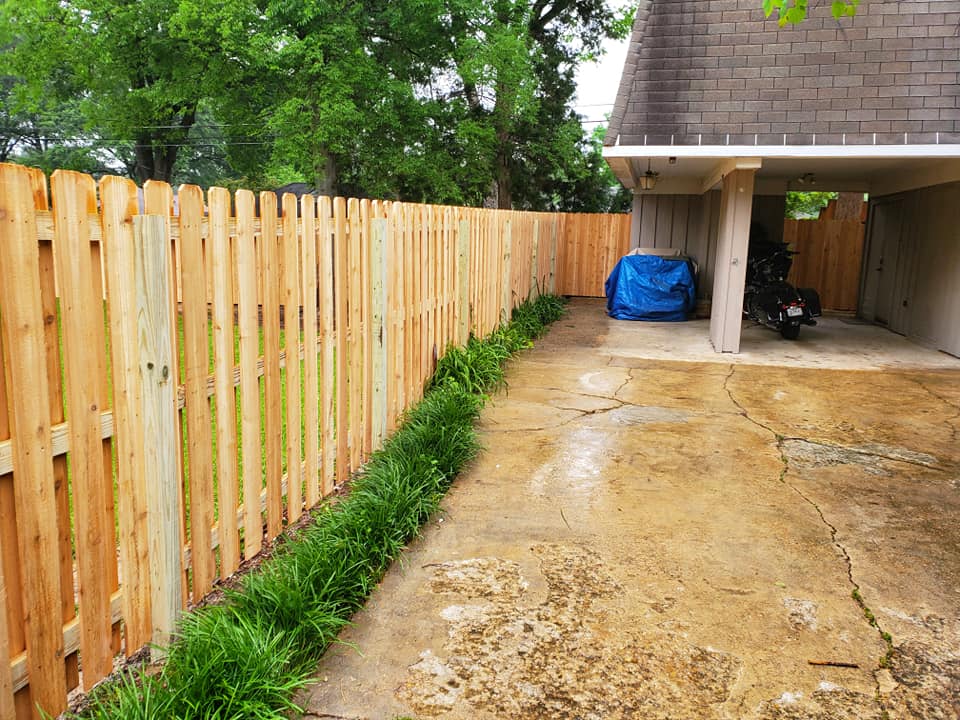 Wood picket fence along driveway and carport area