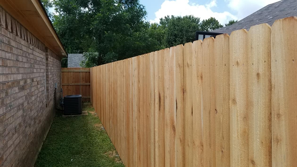 Wood privacy fence in narrow side yard beside brick house